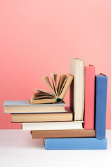 Open book, hardback colorful books on wooden table, red, pink background. Back to school. Copy space for text. Education business concept.