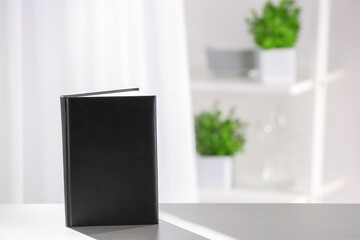 Book with blank cover on blurred background