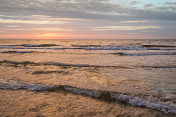Sunset on Baltic Sea white pastel color sky and rough sea.