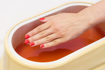Process paraffin treatment of female hands in beauty salon 