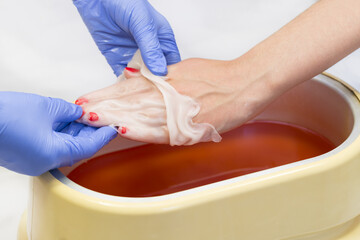 Process paraffin treatment of female hands in beauty salon 
