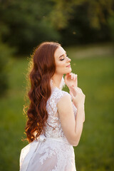 Beautiful redhead Bride playing with her hair. Portprait outdoor in sunset light. Pretty young caucasian redhead girl