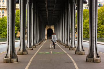 Metal columns and abutments of '' Bir Hakeim '' bridge. People walks and make jogging under the bridge in Paris.The bridge is one of the most famous and historic landmark