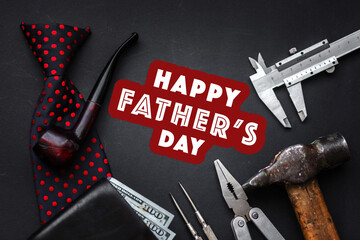 happy father's day text sign with tobacco pipe and tie wallet money and many tools on black rustic background top view. fathers day greeting card concept. flat lay. space for text