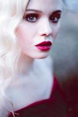 Fashion gorgeous young blonde woman in beautiful red dress in a fairy-tale forest. magic atmosphere. toning shot