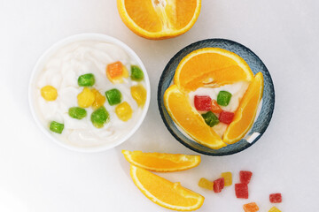 Yogurt with slices of fruit, orange slices and candied fruits on a white background