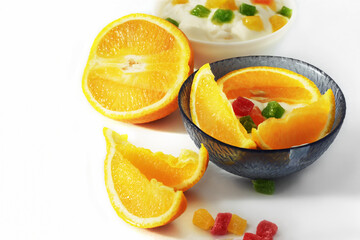 Fototapeta na wymiar Yogurt with slices of fruit, orange slices and candied fruits on a white background