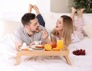 Obraz na płótnie Canvas Happy couple having breakfast in bed
