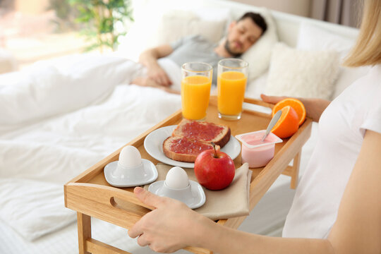 Woman bringing tray with breakfast to bed