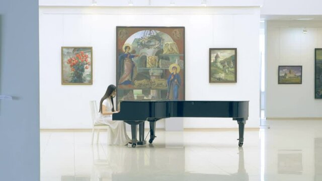 Female pianist playing the piano in picture gallery