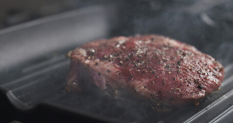 cooking rib eye steak on grill pan, wide photo