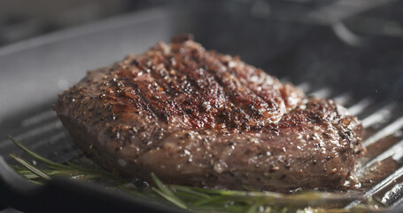 cooking rib eye steak with herbs on grill pan, wide photo