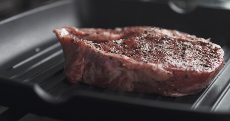 cooking rib eye steak on grill pan, wide photo
