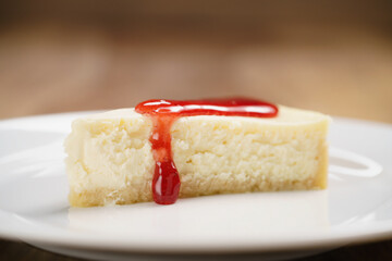 strawberry jam pour on cheesecake on plate on wood table, shallow focus