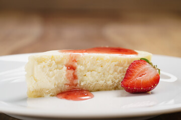 cheesecake with strawberry on plate on wood table, shallow focus