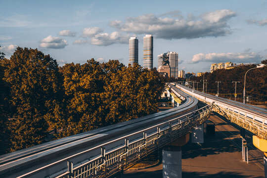 View of empty overground elevated monorail junction in metropolitan city with two twins skyscrapers and "Worker and Kolkhoz Woman" monument in the background, sunny autumn evening, Moscow, Russia