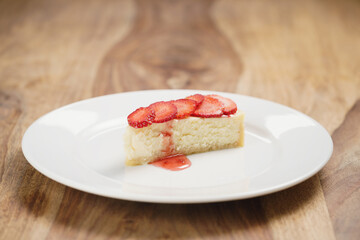Obraz na płótnie Canvas cheesecake with strawberry on plate on wood table, shallow focus