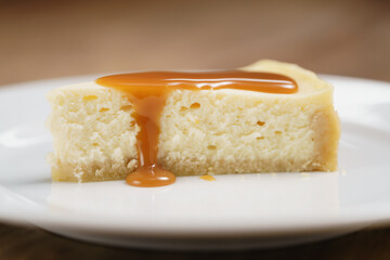caramel sauce pour on cheesecake on plate closeup, shallow focus