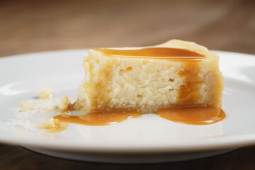 cheesecake with caramel sauce on plate closeup eaten, shallow focus