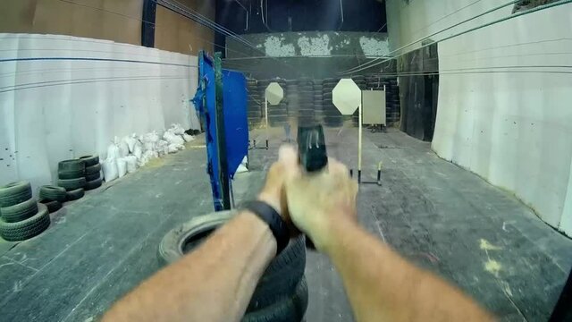 POV: Shooter firing a pistol in an indoor shooting range.