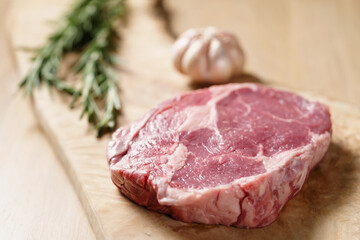 raw rib eye steak on board closeup, shallow focus