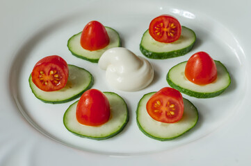 cucumbers, cherry tomatoes and sauсe on a white plate