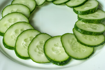 Multiple sliced cucumbers on a white plate