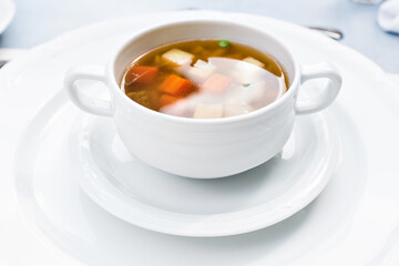 A bowl of delicious beef and barley soup with carrots, tomato, potato, celery, and peas.