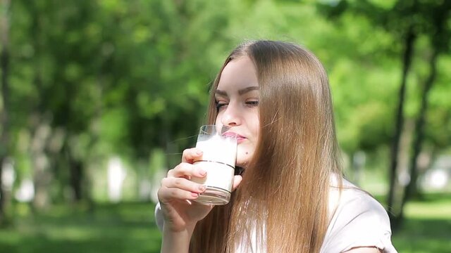 A young beautiful woman drinking milk outdoor.