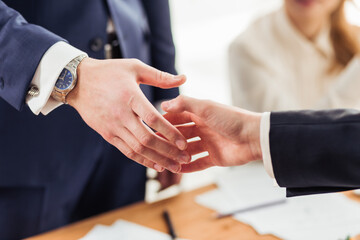 Good deal. Close-up of two business people shaking hands while sitting at the working place