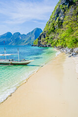 Traditional banca boat in clear water at sandy beach near El Nido, Philippines