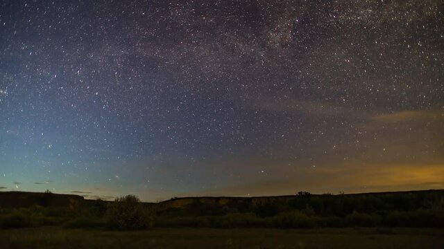 Night sky of stars time lapse during an entire night. Milky way Galaxy, Andromeda Galaxy and stars above grass field and tree.
