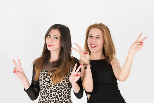 Two modern girls with victory gesture seem satified and happy friends. Half body shot isolated