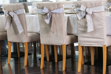 Fototapeta na wymiar Festive wedding ceremony chairs decoration with bows of natural rustic style.