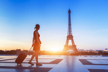Naklejka premium Sylwetka kobiety turysta z walizką blisko wieży eifla, Paryż
