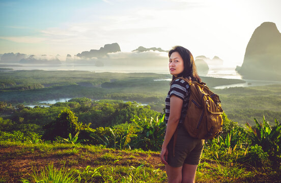Happy young traveler woman backpacker looking backward to camera with a beautiful of nature at top of mountain view point and sea,Freedom wanderlust,Khao Samed Nang Chee Viewpoint,Phang Nga,Thailand.