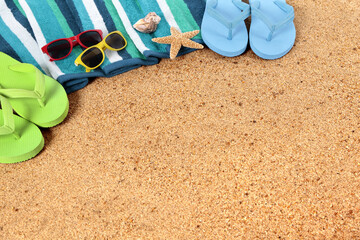 Beach background border with sunbathing towel flip flops  sunglasses and starfish on sand summer couple holiday vacation scene design photo