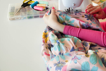 Young woman sewing while sitting at her working place