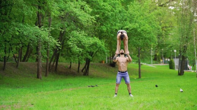 A guy and a girl are doing sports, aerial gymnastics in the park