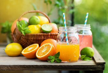 Mix of fresh citrus fruits in basket and juice in glass jars.
