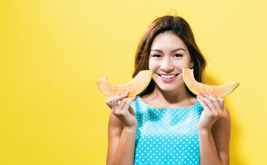 Happy young woman holding slices of cantaloupe