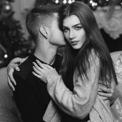 Cute beautiful caucasian young couple sutting at sofa in christmas decorated interior and hugging....