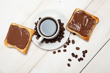 cup of coffee and toast with chocolate on a white wooden table