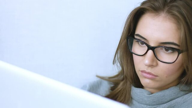 Attractive young woman in glasses using laptop