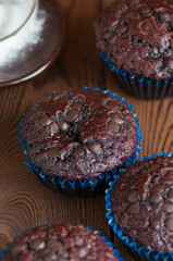 Freshly baked double chocolate muffins on a wooden background with copy space.
