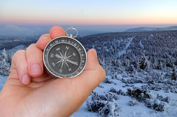 Woman with compass is seeking a right way in mountains