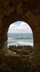 A popular site for photography in Chania - a beautiful hollow window in the destroyed old wall on the shore in Chania (Crete). Vertical view