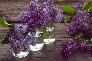 Lilac flowers in jars on the old wooden background
