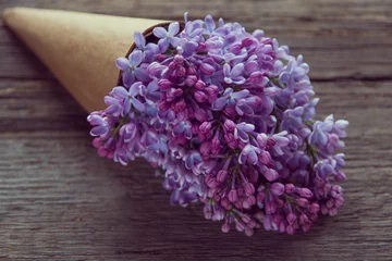 Photo sur Aluminium Lilas Bouquet de fleurs lilas dans un cornet en papier craft sur le vieux fond en bois