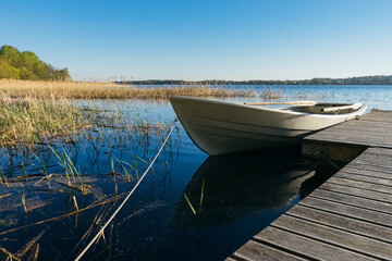 Naklejka premium Small row boat moored at the pier by springtime morning